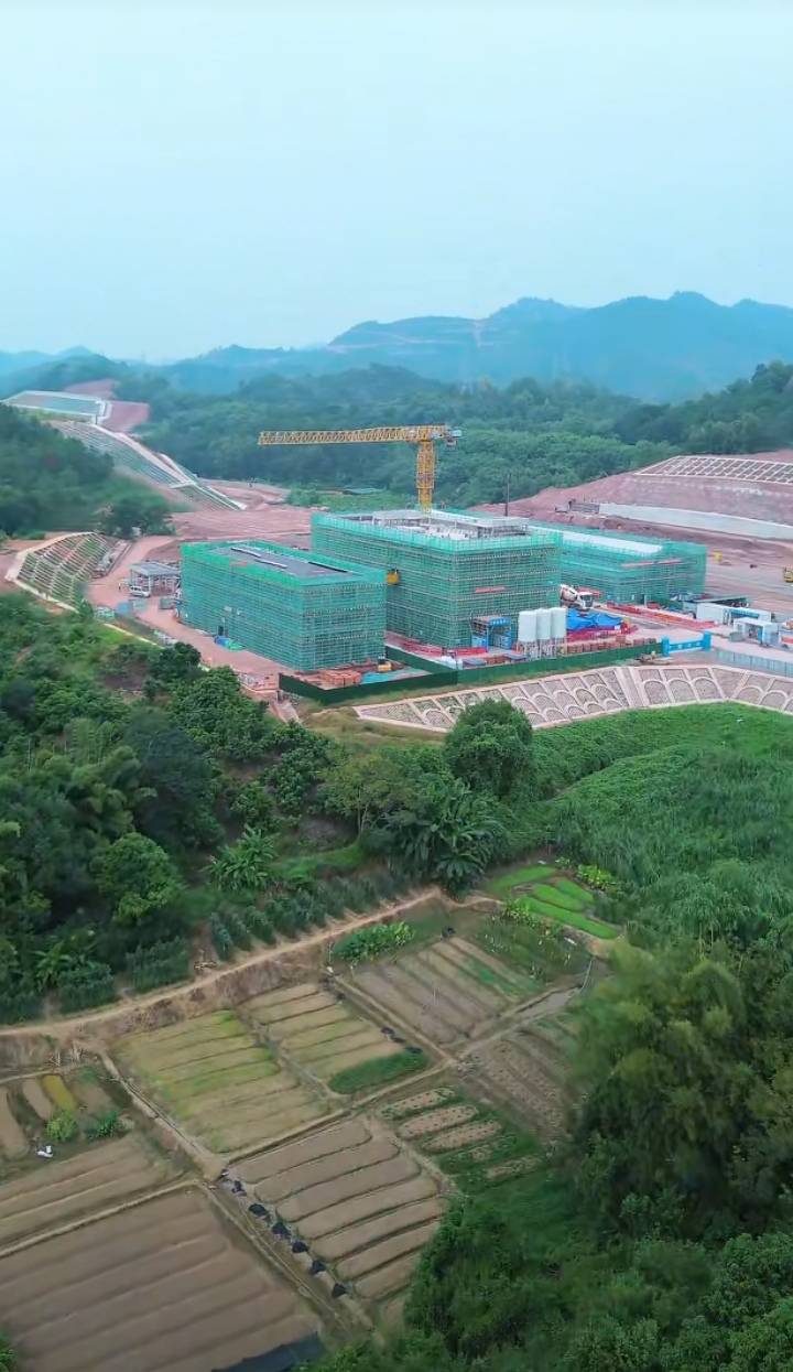 站区施工现场航拍：主体楼群同塔吊，周边系罗定稻田同丘陵