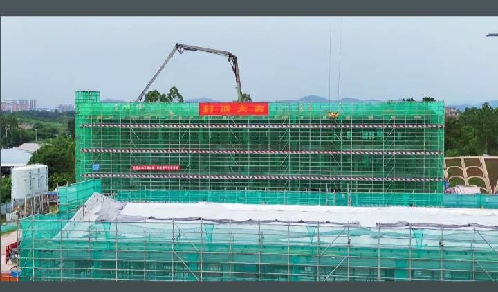 站区楼体挂绿色安全网施工，外墙挂住「热烈祝贺」横幅